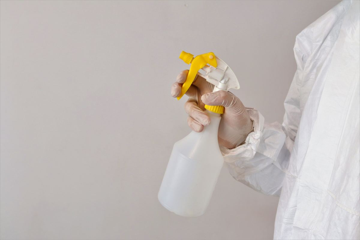 Pest control technician using protective equipment and spray treatment